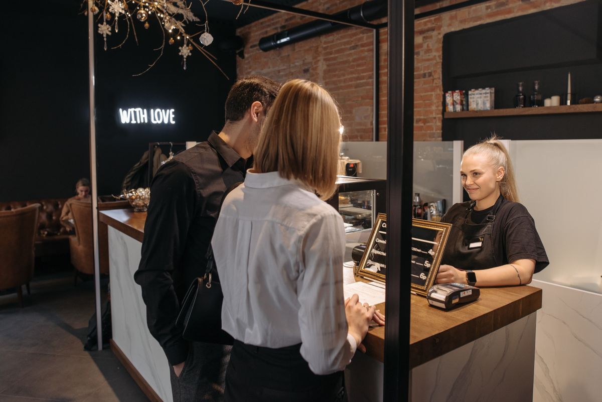 A barista working behind a busy café counter, serving the morning queue